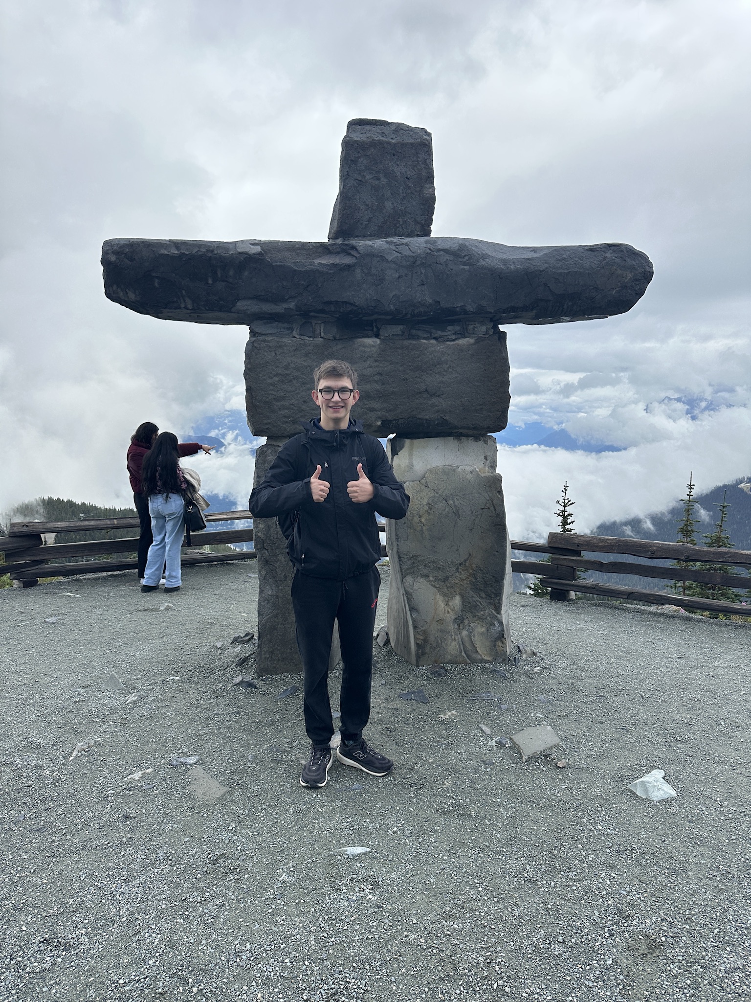 Noah Strauss outdoors beside a large stone landmark